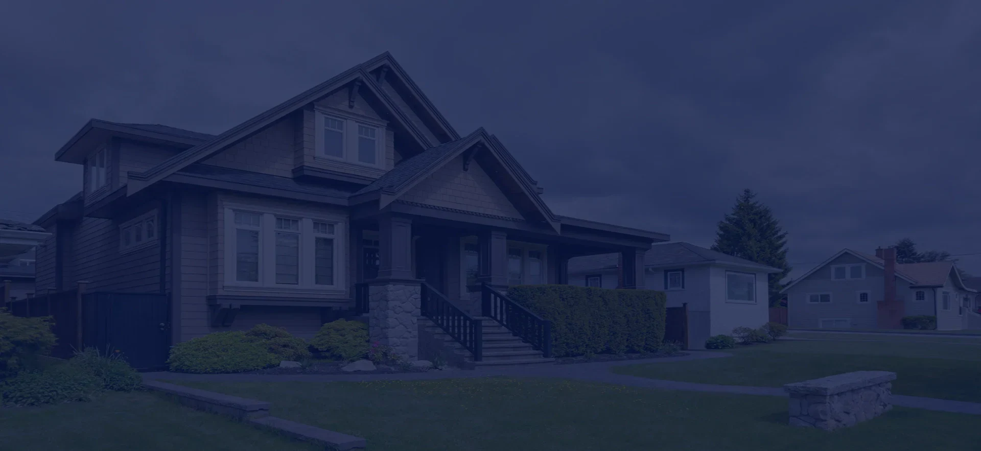 A welcoming suburban house with a stone staircase, lush greenery, and a cloudy sky, surrounded by other homes.